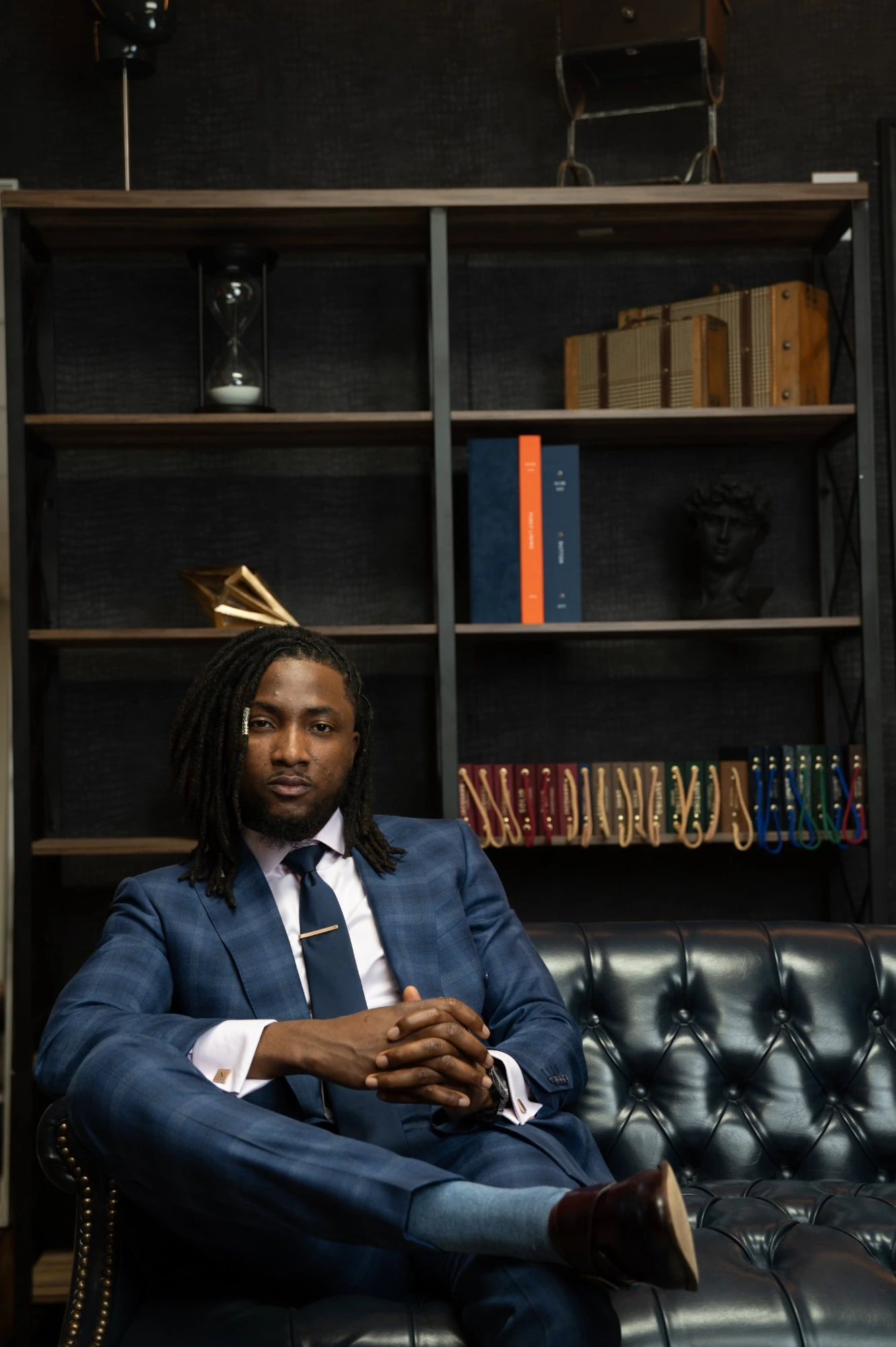 Jay, master tailor and founder of NOIR, seated in the atelier beside the swatch library